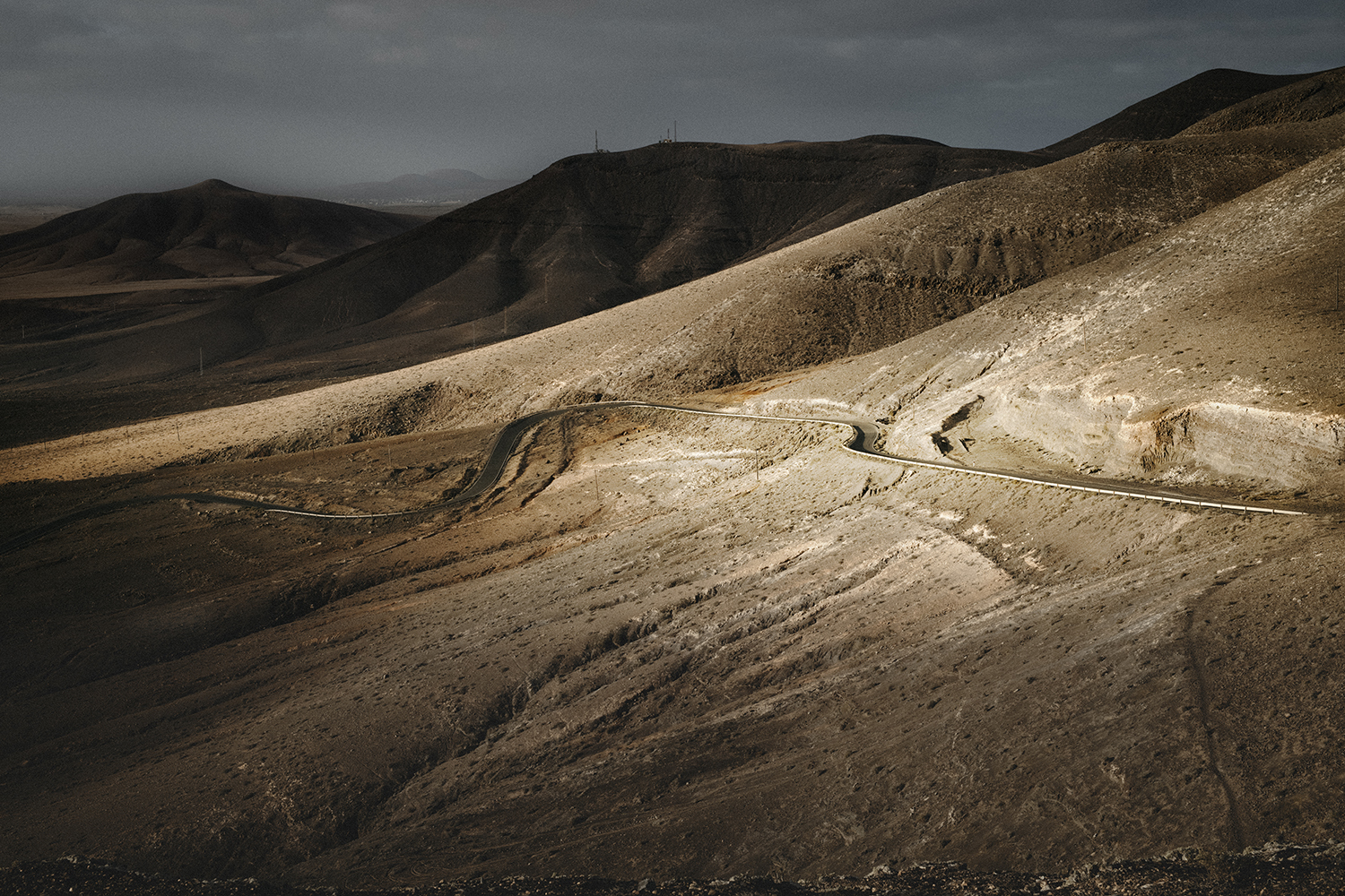 Paisaje desértico volcánico y Carretera sinuosa a través de colinas áridas en Fuerteventura