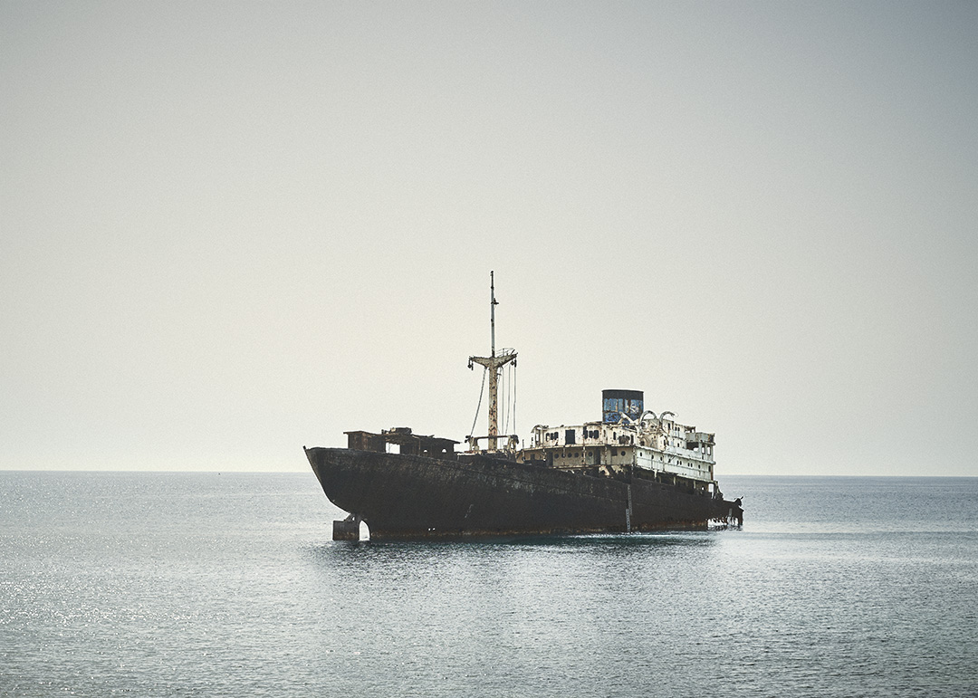 Barco carguero semihundido en aguas tranquilas bajo cielo despejado